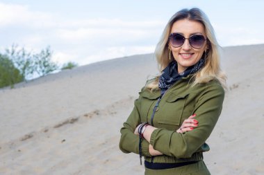 Portrait of a beautiful middle-aged woman in sunglasses and in protective clothing for travel to the desert, looking at the camera.