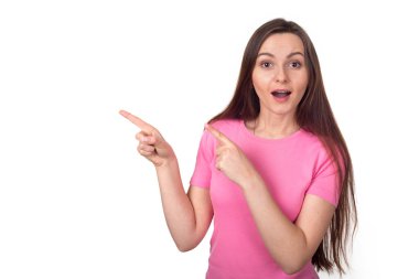 Solu işaret ediyor. Pembe kazaklı genç esmer kadın beyaz arka planda izole bir şekilde parmaklarını yana doğru gösteriyor. Boşluğu kopyala.