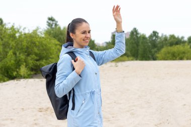 Ne yapıyorsun? Selamlar, mavi ceketli kadın turist ve sırt çantalı kadın doğa yürüyüşü yaparken el sallıyor..