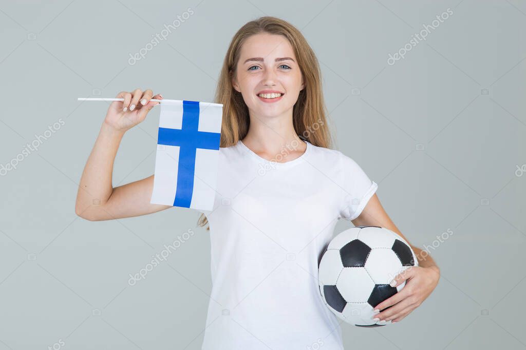 Young woman with the flag of Finland and soccer ball in her hands, looking at camera, isolated on gray background. Finnish women's football.