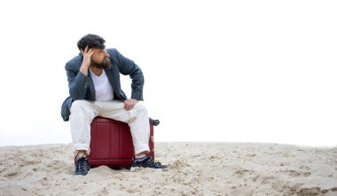 Konsept: Seyahat iptal. Sakallı üzgün adam kumun ortasında bir bavula oturur. Kafasını tutuyor ve nereye gideceğini düşünüyor. Çölde kayboldum..