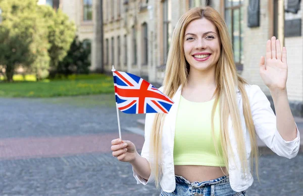Hello, Great Britain friends! Beautiful young woman with the flag of UK. Student studying abroad, learn English.