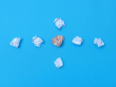 Bir grup buruşuk kağıdın mavi kağıt arka plandaki üst görüntüsü. Takım çalışması veya grup lideri için iş konsepti.