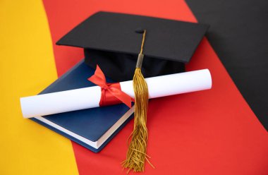 Mezuniyet diploması ve Almanya bayrağının arka planında akademik şapka. Konsept - Mezuniyet Günü. Alman eğitimi.