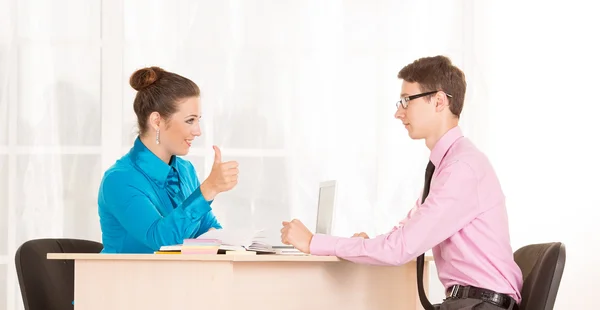 Two young business people having a conversation in the office