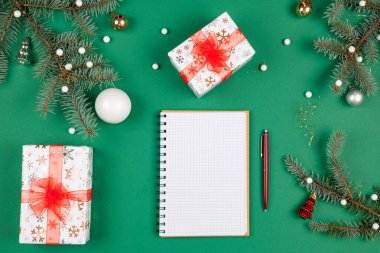 Yeni yıl hedefleri ve iş motivasyonu belirleniyor. Not defteri ve kalem, noel hediyelerinin yanında. Fotokopi alanı olan yeşil bir arka planda. Noel Baba 'ya mektup ve alışveriş listesi. Tatil planlaması.