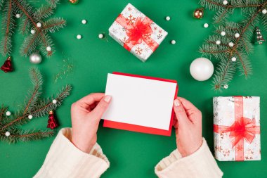 Noel Baba 'ya mektup. Noel ağacıyla çevrili süslemelere karşı bayanların elinde Noel kartı ve yeşil arka planda hediyeler var. Yeni yıl tebrik kartı ve hediyeleri..