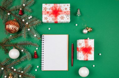 Yeni yıl hedefleri ve iş motivasyonu belirleniyor. Not defteri ve kalem, noel hediyelerinin yanında. Fotokopi alanı olan yeşil bir arka planda. Noel Baba 'ya mektup ve alışveriş listesi. Tatil planlaması.
