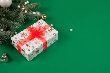 Parlak kırmızı kurdeleli ve şenlikli dekorlu güzel paketlenmiş Noel hediyeleri. Bayram tebrikleri için bolca fotokopi alanı olan yeşil arkaplan. Yeni yıl hediyeleri.