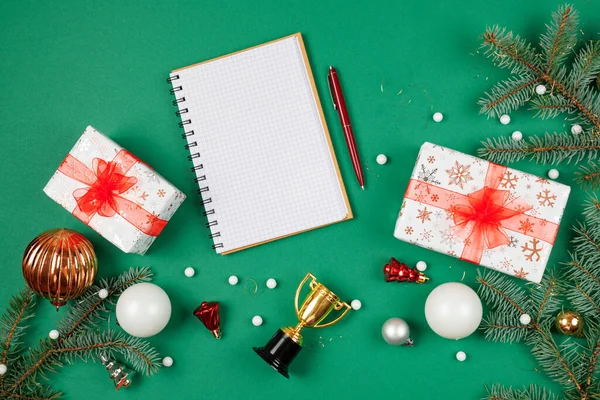 Yeni yıl hediyeleri ve rüyalar listesi. Noel yeşili arka planda fotokopi alanı olan bir not defteri. Üst görüntü fotoğrafı.