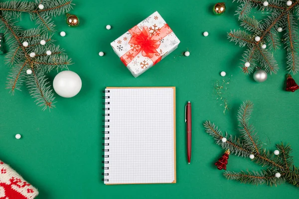Yeni yıl hedefleri ve iş motivasyonu belirleniyor. Not defteri ve kalem, noel hediyelerinin yanında. Fotokopi alanı olan yeşil bir arka planda. Noel Baba 'ya mektup ve alışveriş listesi. Tatil planlaması.