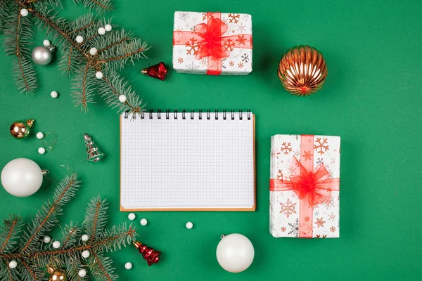 Yeni yıl hedefleri ve iş motivasyonu belirleniyor. Not defteri ve kalem, noel hediyelerinin yanında. Fotokopi alanı olan yeşil bir arka planda. Noel Baba 'ya mektup ve alışveriş listesi. Tatil planlaması.