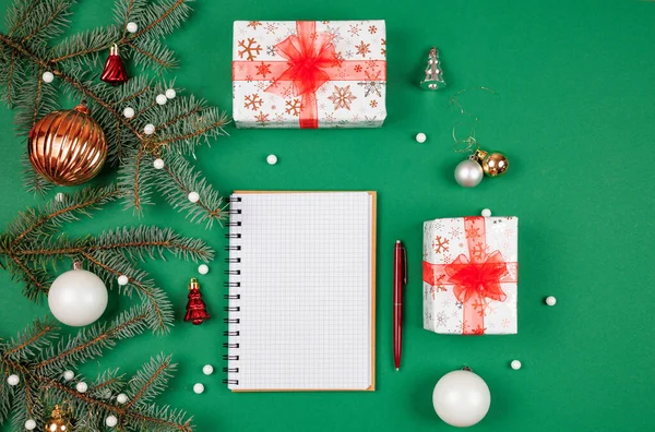 Yeni yıl hedefleri ve iş motivasyonu belirleniyor. Not defteri ve kalem, noel hediyelerinin yanında. Fotokopi alanı olan yeşil bir arka planda. Noel Baba 'ya mektup ve alışveriş listesi. Tatil planlaması.