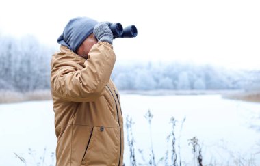 Dürbünlü bir ekolojist donmuş kış ormanını gözetliyor. Çevresel araştırmalar ve doğada doğal hayatı koruma. Kış doğa araştırmaları ve çevre koruma çalışmaları.