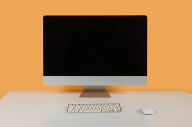 Masaüstünde turuncu bir arkaplanda kişisel bilgisayar monitörü.