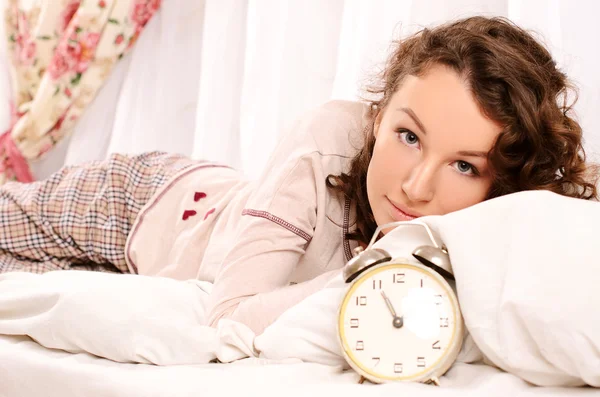 Young woman lying on bed and alarm clock — Stock Photo, Image