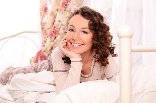 Lachende jonge aantrekkelijke vrouw liggend op bed — Stockfoto