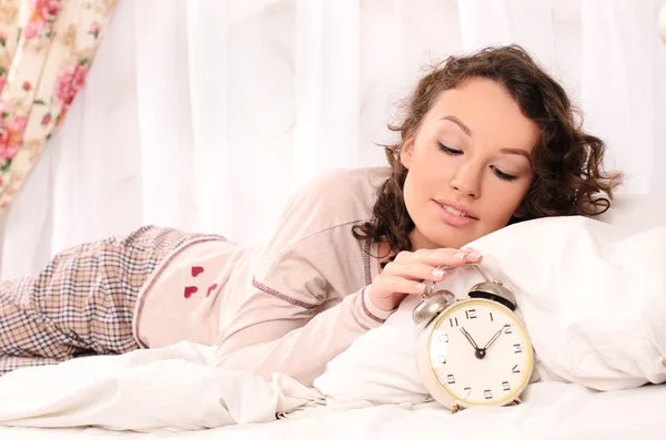 Young woman lying on bed and alarm clock — Stock Photo, Image
