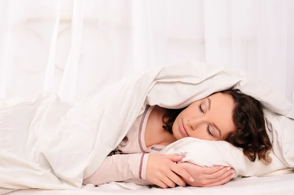 Mooie jonge vrouw slapen op witte bed — Stockfoto