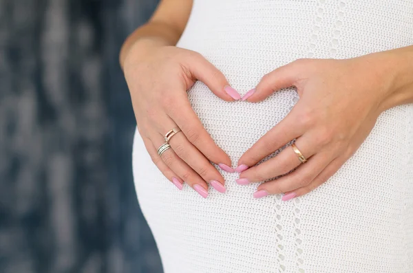 Estómago embarazada con el corazón de las manos — Foto de Stock