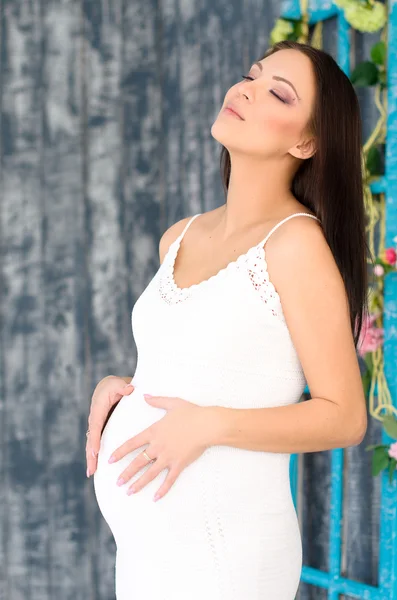 Zwangere vrouw in een witte zomerjurk — Stockfoto