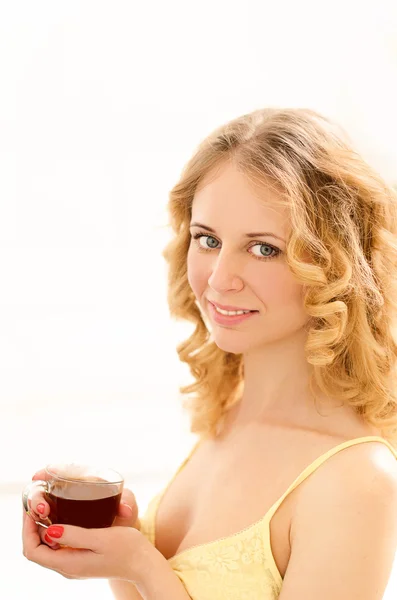 Jonge lachende vrouw met kopje thee in zonlicht — Stockfoto