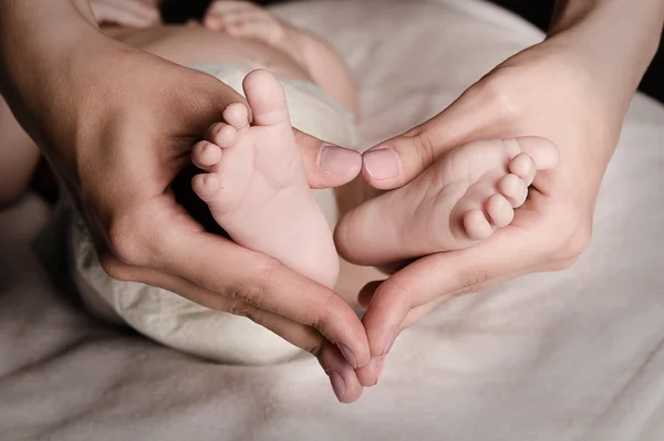 Mamma håller foten av nyfött barn — Stockfoto