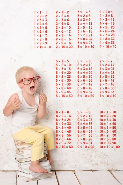 Niño se sienta en libros pintados de blanco —  Fotos de Stock