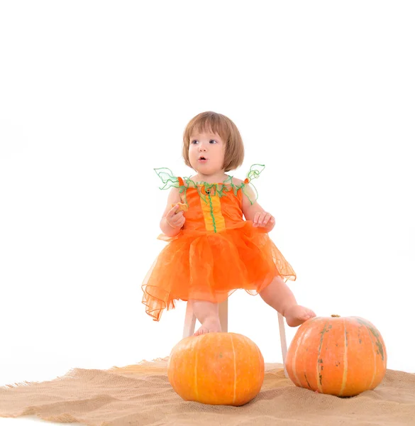 Petite fille en costume orange avec des citrouilles — Photo