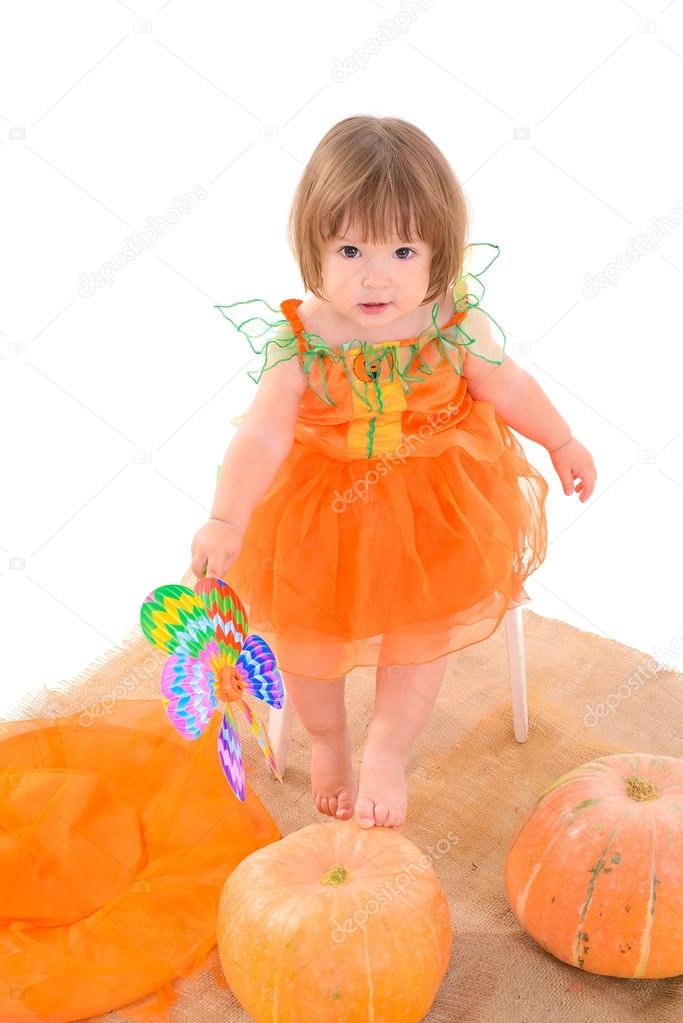 Little girl in orange costume with pumpkins