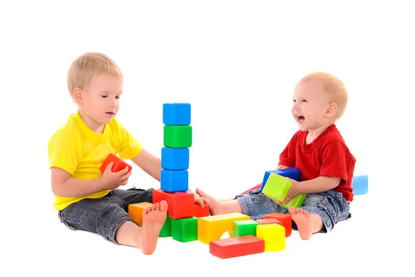 Two brothers build toy building of colored cubes — Stock Photo, Image