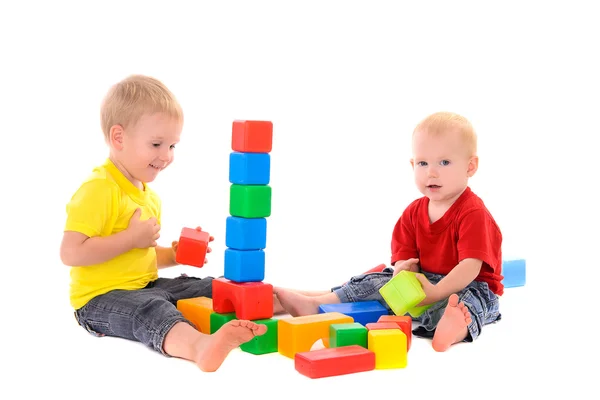 Two brothers build toy building of colored cubes — Stock Photo, Image