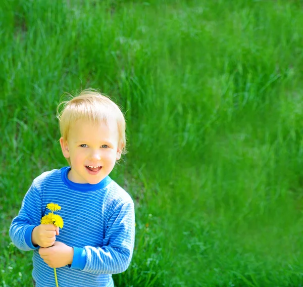 Blonde jongen op voorjaar groen gras achtergrond — Stockfoto