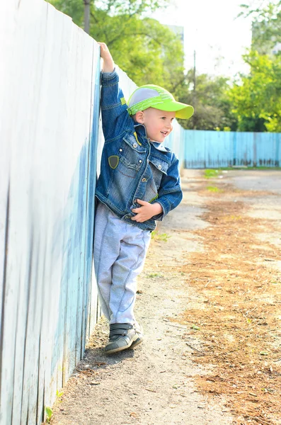 Kleine jongen op hek buiten bedrijf — Stockfoto