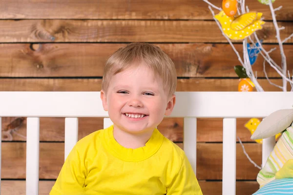 Laughing boy sitting on bench indoors — Stock Photo, Image