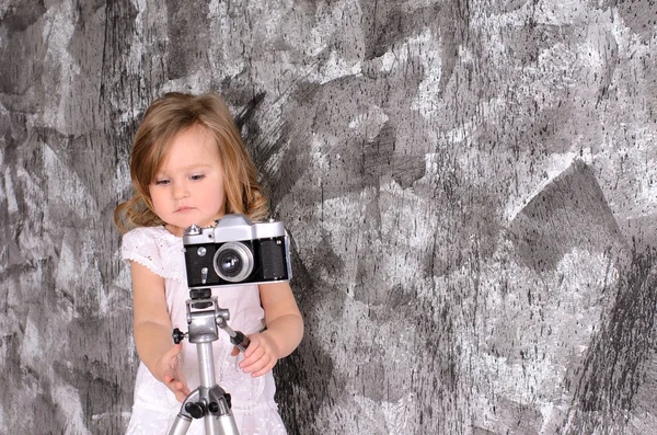 Petite fille avec caméra rétro sur rack à l'intérieur — Photo