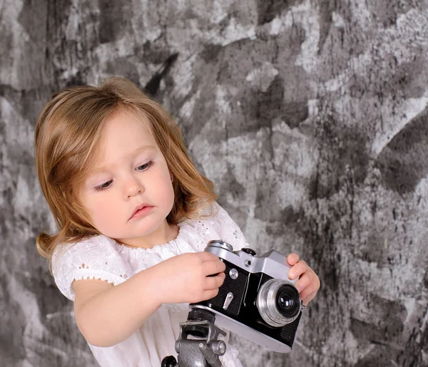 Holčička s retro fotoaparát na stojanu interiéru — Stock fotografie