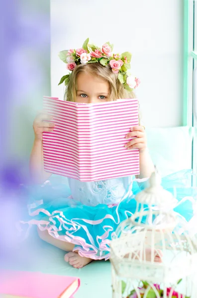 Malá holčička pokryté věnec čtení knihy — Stock fotografie