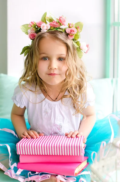 Little girl with wreath and pink books — Stock Photo, Image