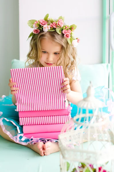 Kleines Mädchen mit Kranz und Bücherstapel — Stockfoto