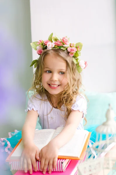Bambina sorridente con ghirlanda e libri — Foto Stock