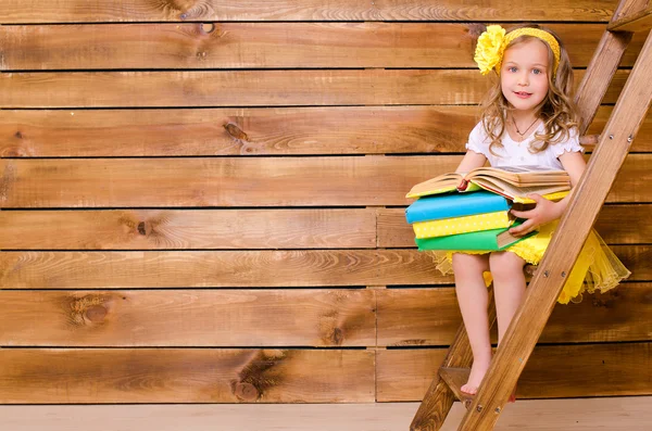 Bambina con pila di libri seduta sulla scala — Foto Stock