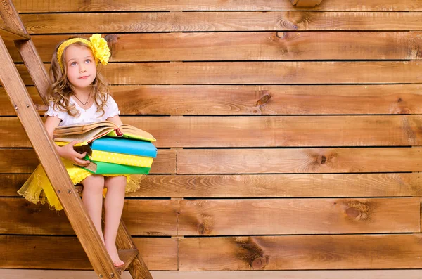 Kleines Mädchen mit Bücherstapel auf Leiter — Stockfoto