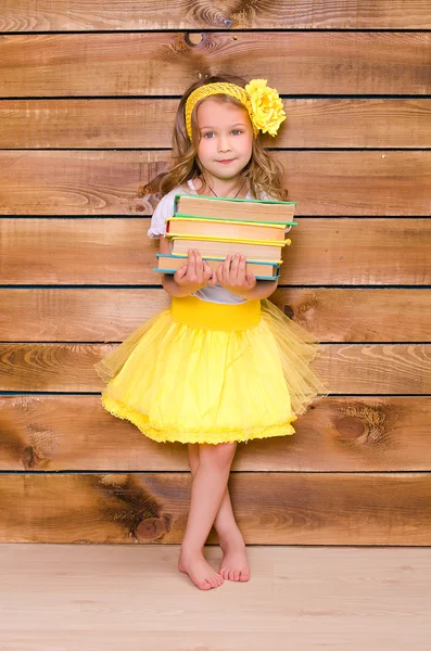 Kleines Mädchen im gelben Tutu mit einem Stapel Bücher — Stockfoto