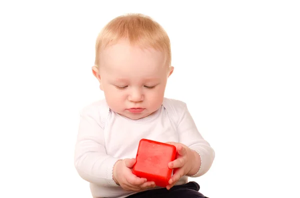 Bebé niño en blanco jugando con juguete bloque rojo — Foto de Stock