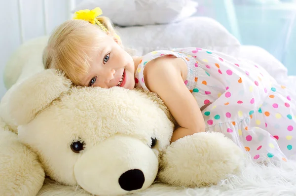 Küçük kız büyük beyaz oyuncak ayı kucaklayan — Stok fotoğraf