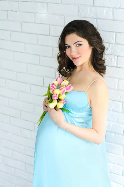 Young attractive pregnant woman with flowers — Stock Photo, Image