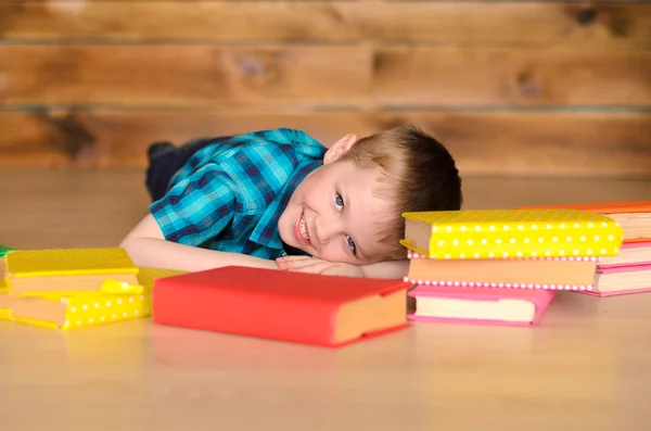 Kleiner Junge liegt auf dem Boden neben Büchern — Stockfoto