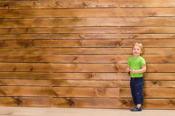 Kleiner Junge auf braunem Holzwandhintergrund — Stockfoto