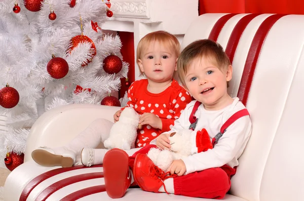 Little children sitting at christmas tree Stock Photo